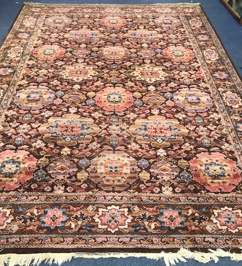 A Persian-style aubergine ground carpet, all over woven with large stylised flowerheads, 350 x 249cm (worn in places)